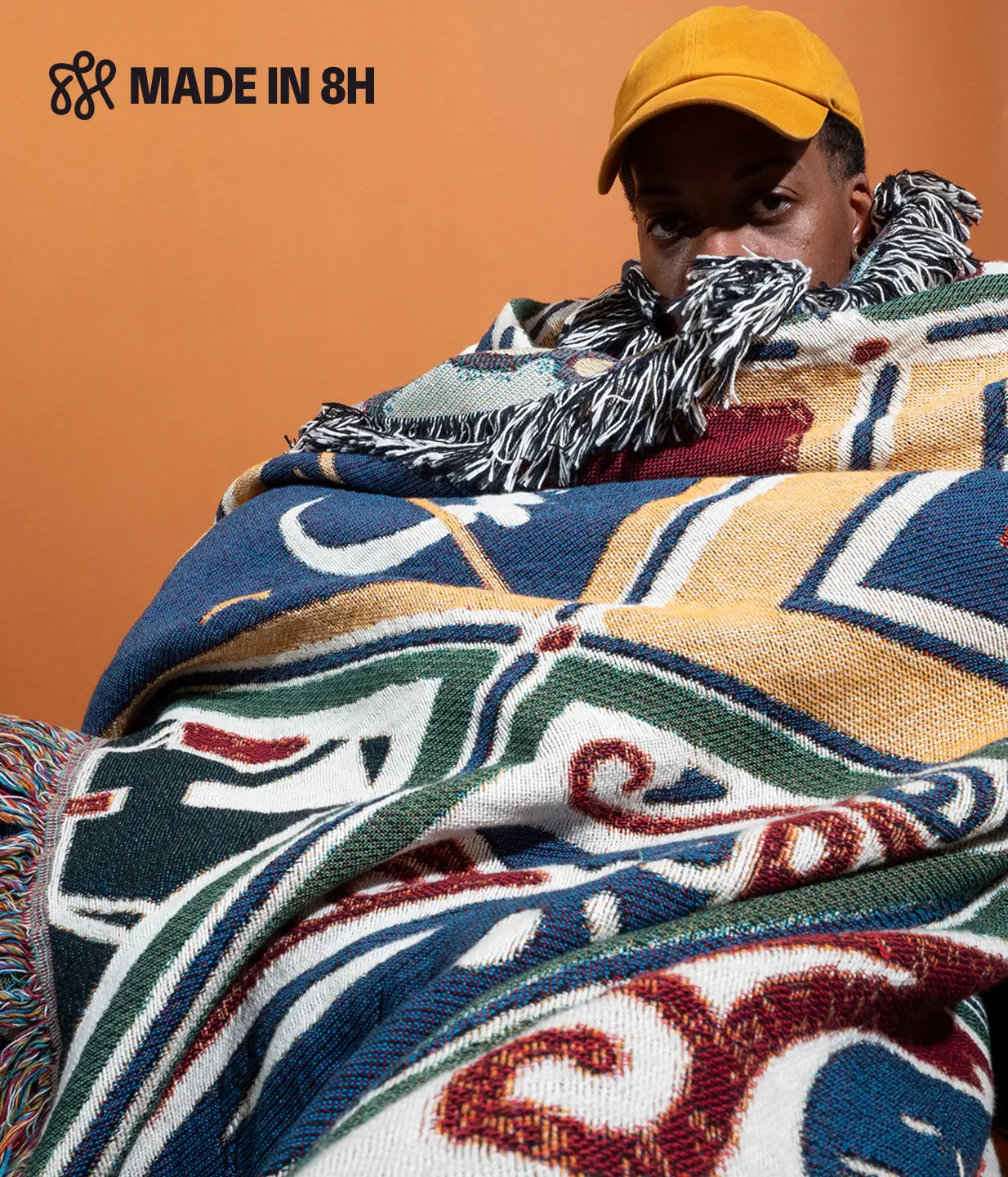 Model wearing a textile we designed against a fun orange background wearing a dull yellow hat
