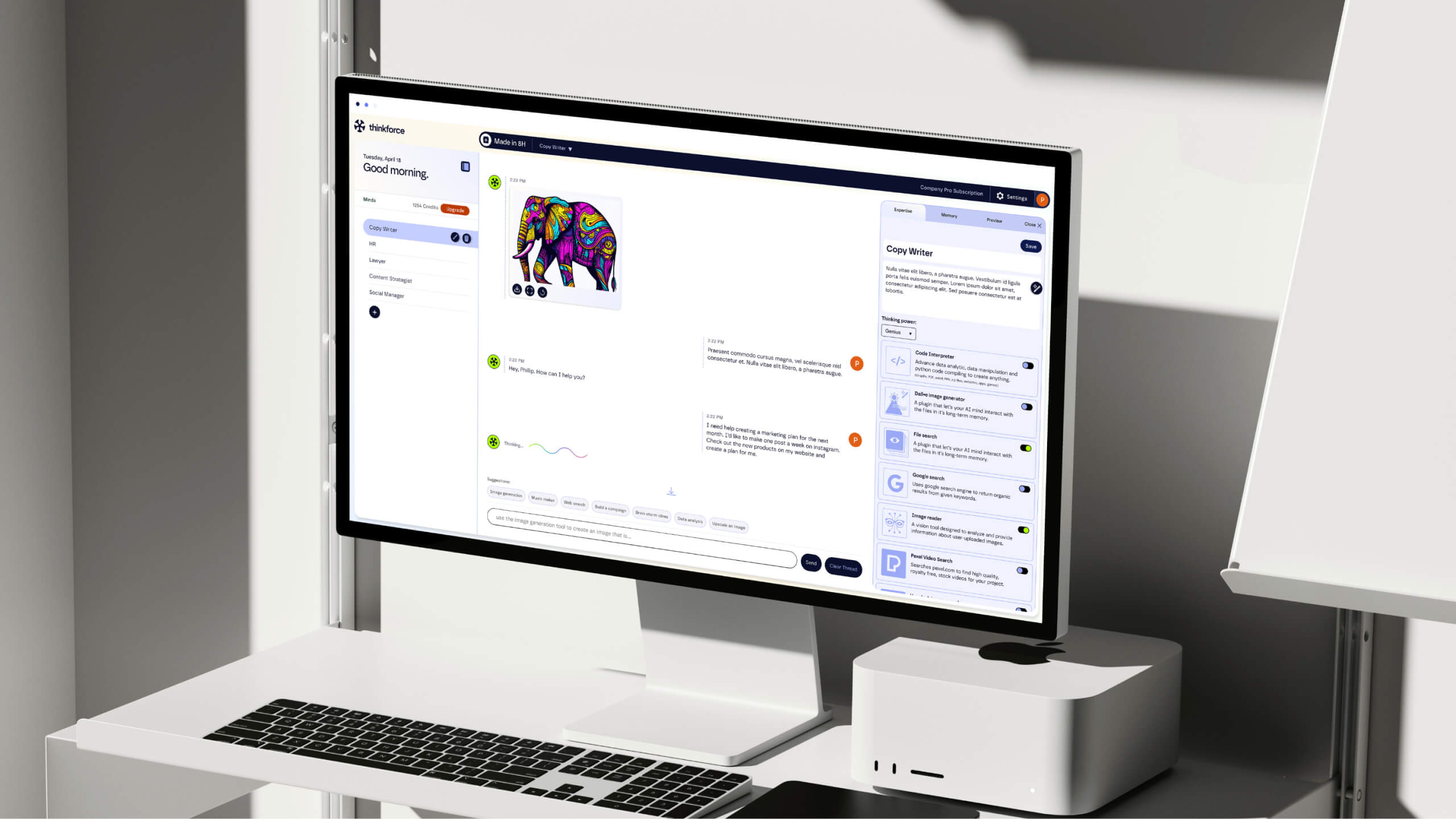 A modern workspace featuring an Apple Mac Studio setup with a widescreen monitor displaying an AI-based software interface. The screen shows a colorful, abstract elephant illustration alongside a chatbot-style conversation.