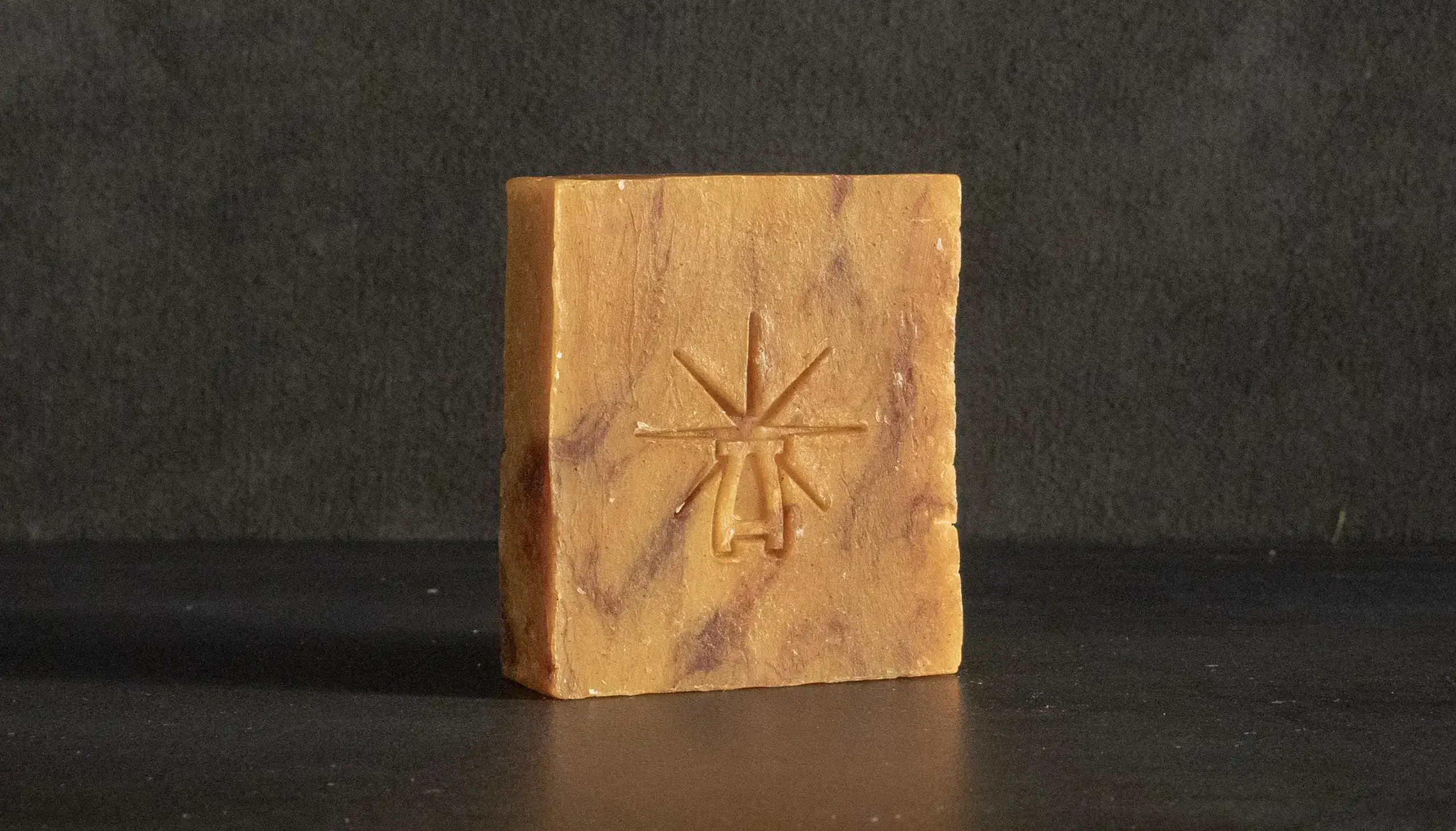 a single bar of soap stands alone in a dark marble smokey environment